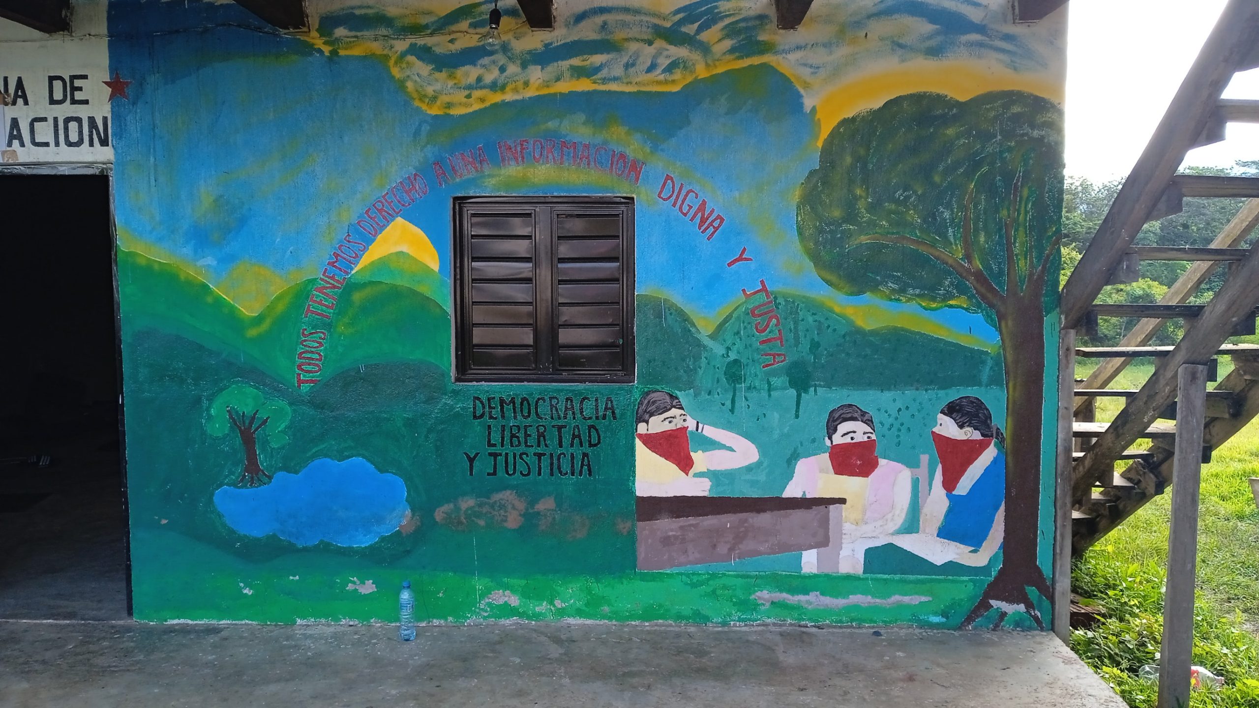 Mural showing a forest and three Zapatistas whose faces are covered
